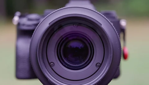 Close-up of a purple camera lens with concentric glass elements visible through the front element.