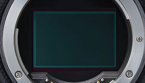 Close-up of a camera's mirror box interior showing the exposed sensor with a green-tinted protective frame.
