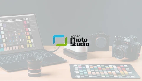 Zoner Photo Studio logo displayed on a studio desk setup with professional cameras and color reference tools.
