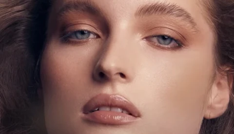 Close-up portrait of a woman with pale skin and blue eyes looking downward with a contemplative expression.