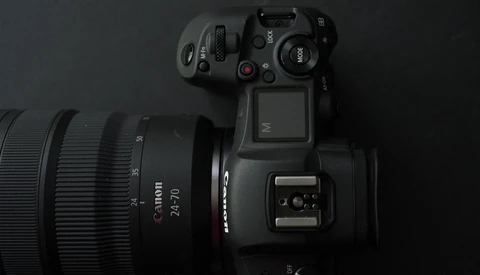 Canon EOS R5 mirrorless camera with Canon RF 24-70mm lens mounted, photographed from above against dark background.