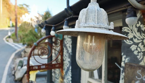 Weathered vintage-style wall sconce with frosted glass cylinder and metal cap mounted on an ornate bracket.