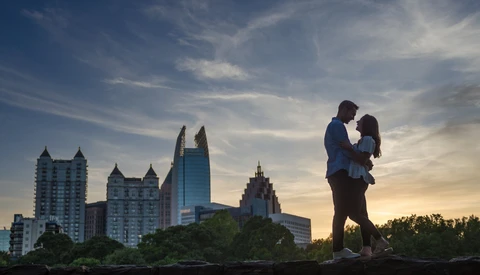 Silhouetted couple embracing against a city skyline at golden hour.