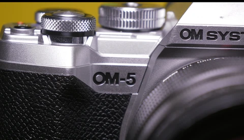 Close-up detail of OM-5 and OM SYS camera bodies showing textured grip and control dials.
