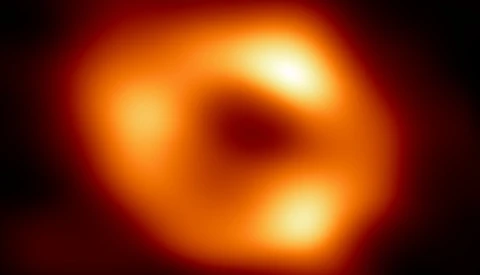 First photograph of a black hole, showing a glowing orange and red ring structure with a dark center.