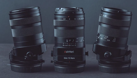 Three vintage manual focus lenses arranged side by side, displaying their barrels, focus rings, and aperture scales against a gray background.