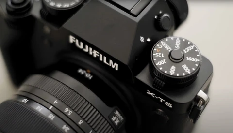 Fujifilm X-T5 camera with attached lens and exposure compensation dial visible on top plate.