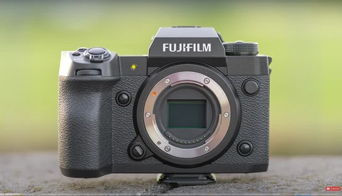 Fujifilm X-H2S mirrorless camera body with exposed sensor and lens mount against blurred green background.