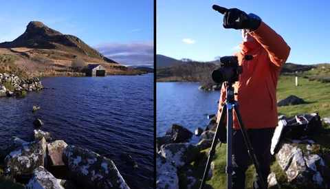 Photographer operating a camera on tripod while framing a mountain landscape with lake below.