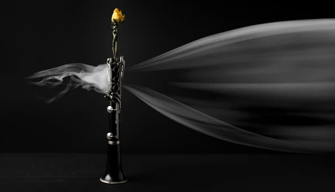 Brass trumpet with smoke billowing from the bell against a black background.