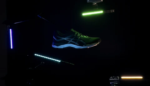 Neon light painting setup with glowing tubes and illuminated running shoe against dark background.