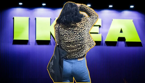Woman in leopard print jacket and jeans posing against neon-lit signage with purple and green lighting.