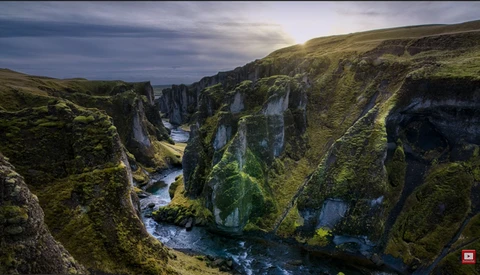Deep canyon with moss-covered basalt cliffs and a winding river flowing through the valley floor.