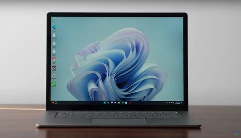 Screenshot of Windows 11 desktop displaying abstract blue and white fluid wallpaper on laptop screen.
