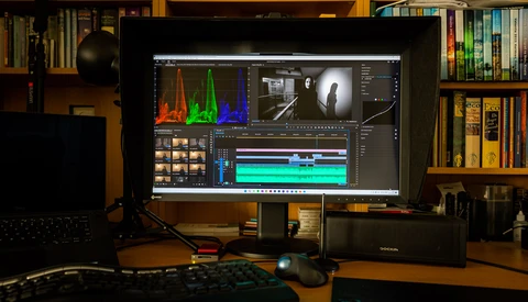 Video editing workstation with color grading software displaying audio waveforms and timeline on a large monitor.