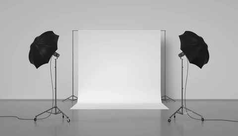 Professional studio setup with white seamless backdrop, two softbox umbrellas on tripod stands, and gray floor.