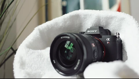 Sony α7 mirrorless camera with attached lens, cradled in white fluffy material.