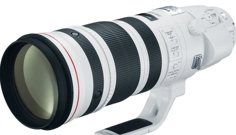 White telephoto zoom lens with black grip and control rings on white background.