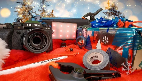 Fujifilm X-T5 camera with LED light and creative photography accessories arranged on red fabric with holiday decorations.