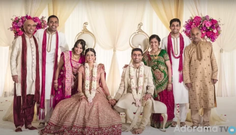 Extended family group portrait in coordinated traditional Indian wedding attire with magenta and cream colors.