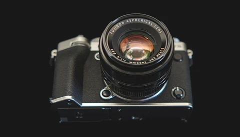 Vintage rangefinder camera with fast prime lens mounted, shot against dark background from above.