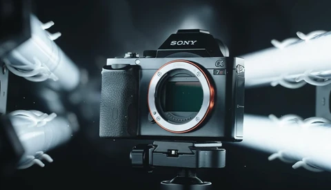Sony mirrorless camera mounted on tripod with white feathers blurred in motion around it.