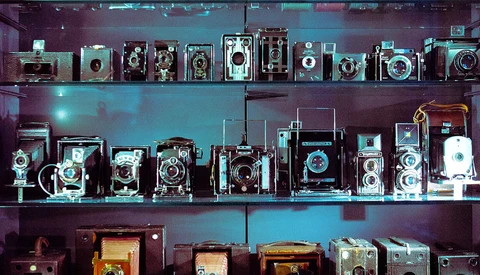 Display shelves with vintage cameras and photography equipment arranged in museum-style lighting.