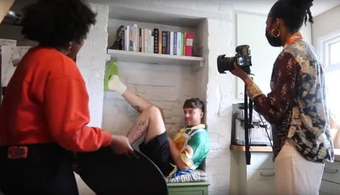 Behind-the-scenes photo shoot in a home interior with camera operator and lighting setup.