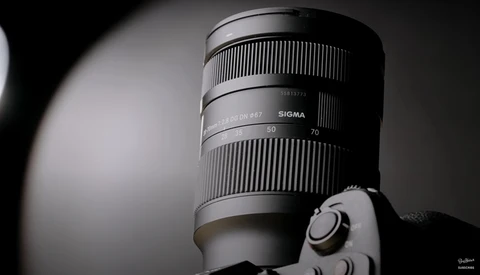 Sigma telephoto lens mounted on camera body, shown in black and white studio lighting.
