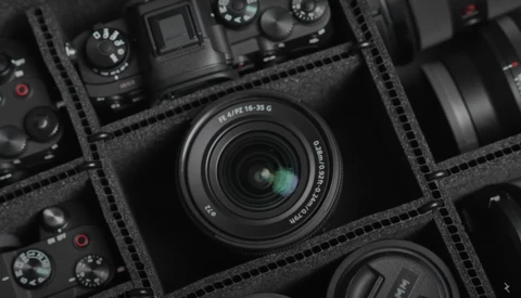 Leica 18-25mm zoom lens displayed in foam equipment case with camera bodies and accessories.