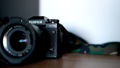 Fujifilm X-T5 mirrorless camera with attached lens on wooden surface.