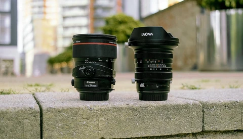 Three camera lenses arranged on a concrete ledge with urban buildings blurred in the background.