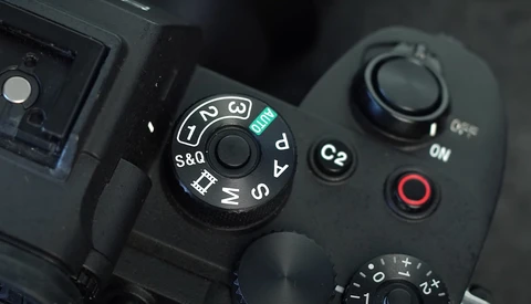 Close-up of a camera's mode dial and control buttons showing exposure compensation and shooting mode settings.
