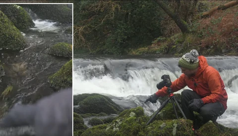Photographer with tripod capturing a flowing waterfall in a moss-covered forest landscape.