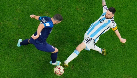 Overhead view of two soccer players competing for the ball on grass field.