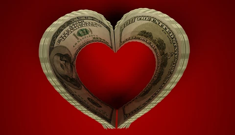 Two rolled dollar bills forming a heart shape with a solid red heart in the center against a red background.