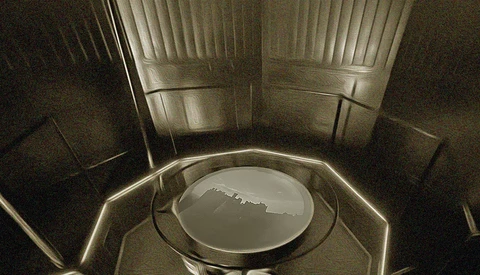 Interior view looking up at a car hood and windshield from below, showing vertical blinds and dashboard.