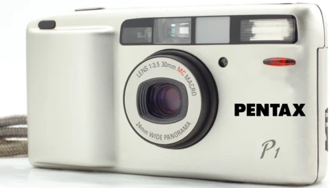 Pentax P1 compact film camera with fixed 35mm lens against white background.