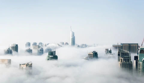 Skyscrapers emerging from dense fog layer in an urban skyline during morning mist.