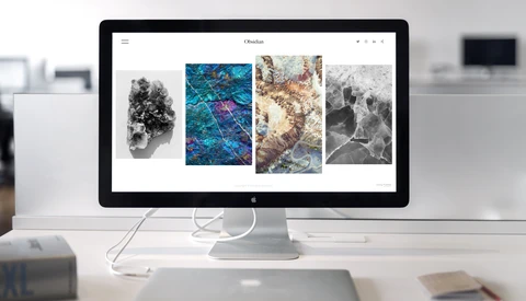 Desktop monitor displaying a portfolio website with four landscape photographs arranged in a grid layout.