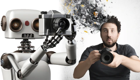 Robotic camera operator holding a cinema camera next to a man in a black shirt holding a mirrorless camera.