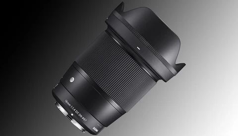 Black telephoto lens with hood mounted, displayed at an angle against a gradient gray background.