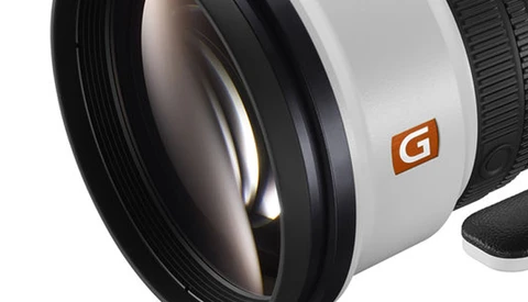 Close-up view of a wide-angle camera lens with glass elements visible and an orange G-series logo on the white barrel.