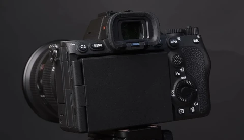 Professional mirrorless camera shown from rear three-quarter angle against dark background.