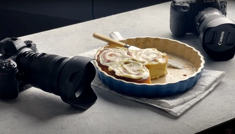 Flat lay of photography equipment and a baked pie on a concrete surface.