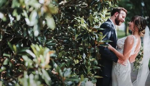 Bride and groom embrace among olive trees during outdoor wedding ceremony.