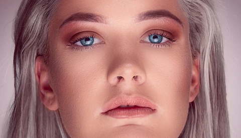 Close-up portrait of a person with gray hair and blue eyes looking slightly downward.