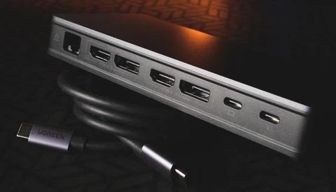 USB-C hub with multiple ports displayed next to a connected cable against dark background.