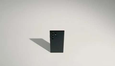 Black smartphone displayed at an angle against a light background, casting a distinct shadow.