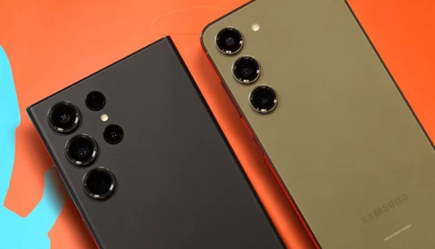 Two smartphones with triple camera systems photographed against an orange and blue background.